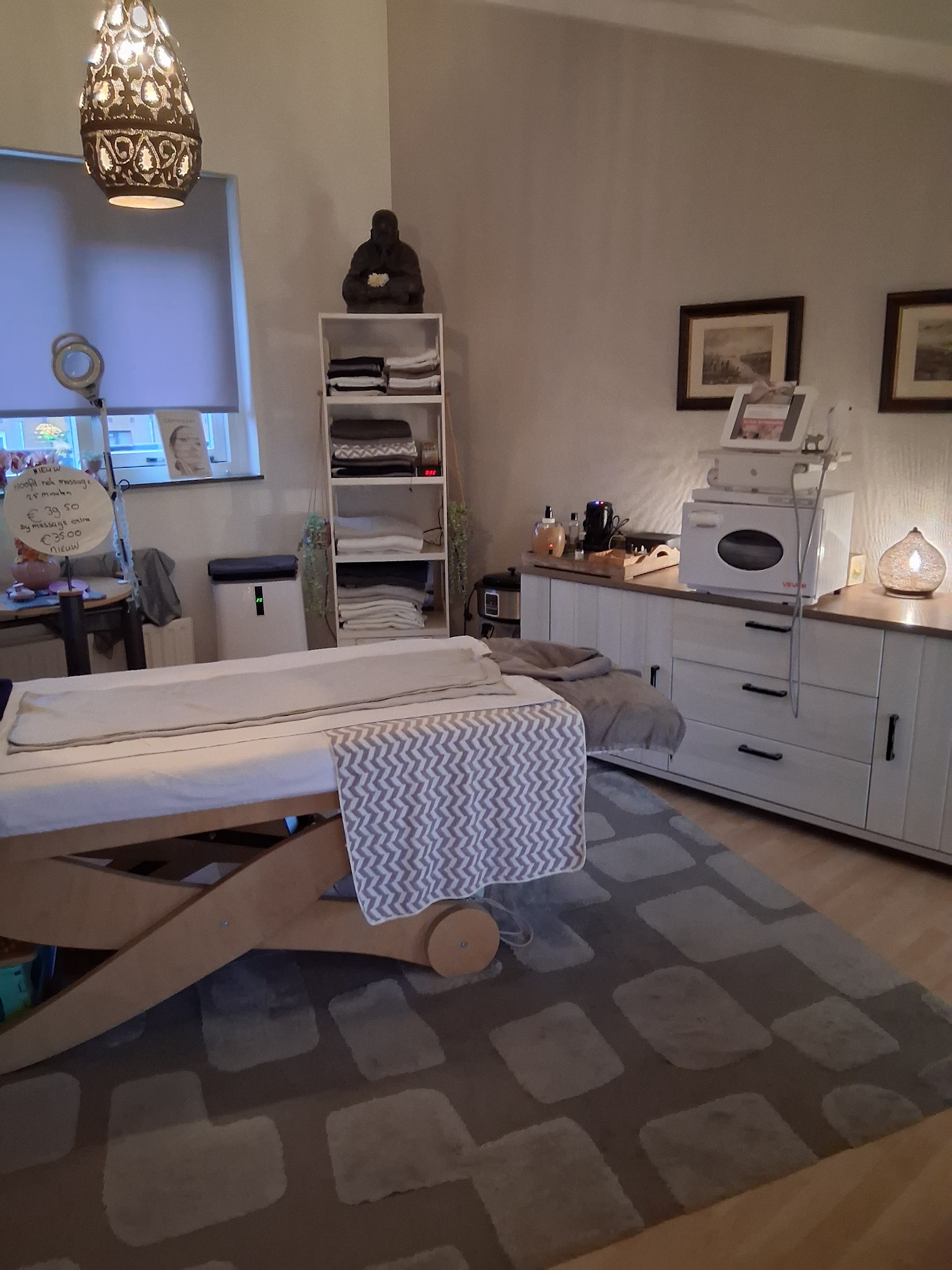 De behandelkamer met massagetafel, kast met handdoeken en een lantaarnlamp aan het plafond